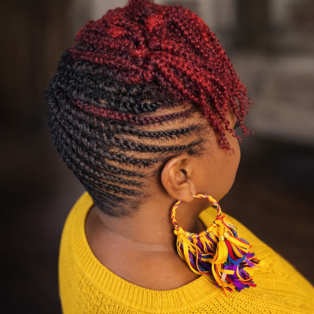 Woman with braided hair wearing a yellow sweater and colorful earrings.